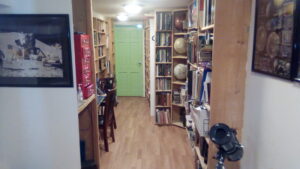 Interior view of the studio library room. It's a long corridor, lined with bookshelves. There's also a desk and closet.