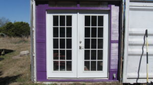 Front entrance to studio: french doors with louvered vents on either side. The doors are white, the trim is purple.