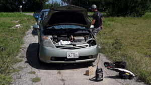 Green Prius with hood up and headlight removed.